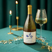 Bottle of Babylonstoren Chardonnay wine with a glass on a teal tablecloth, candles in the background