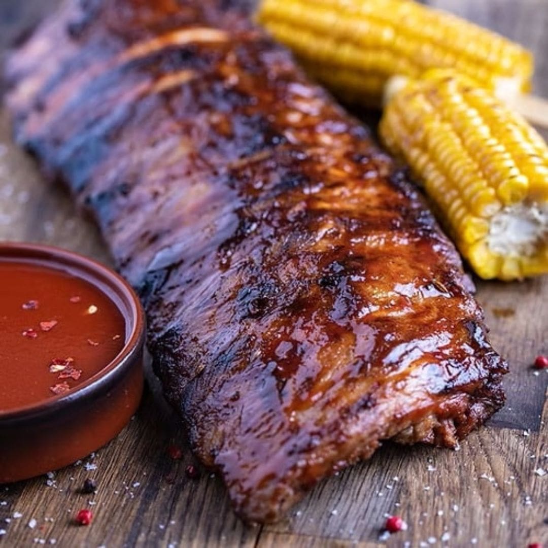 Barbecue ribs with corn on the cob on a wooden surface. Braai meats.