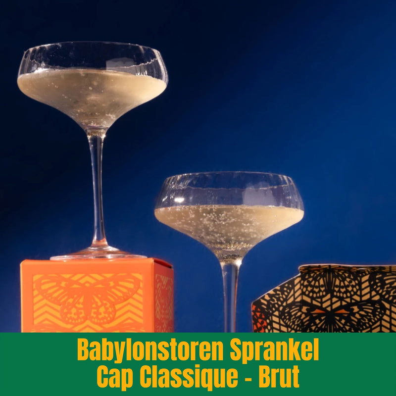 Two glasses with a drink on an orange and black box against a blue background, with text 'Babylonstoren Sprankel Cap Classique - Brut' at the bottom.