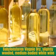 Bottles of Babylonstoren Viognie Dry white wine on a wooden surface with a blurred background.