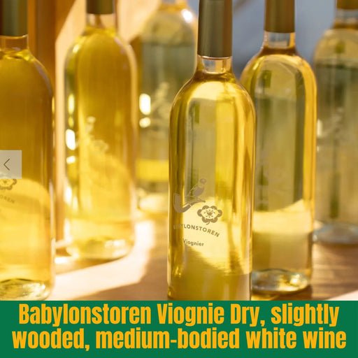 Bottles of Babylonstoren Viognie Dry white wine on a wooden surface with a blurred background.