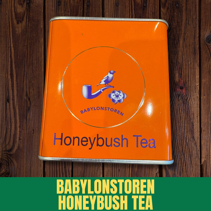Orange tin of Babylonstoren Honeybush Tea on a wooden surface