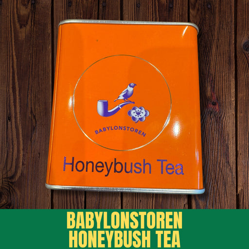 Orange tin of Babylonstoren Honeybush Tea on a wooden surface