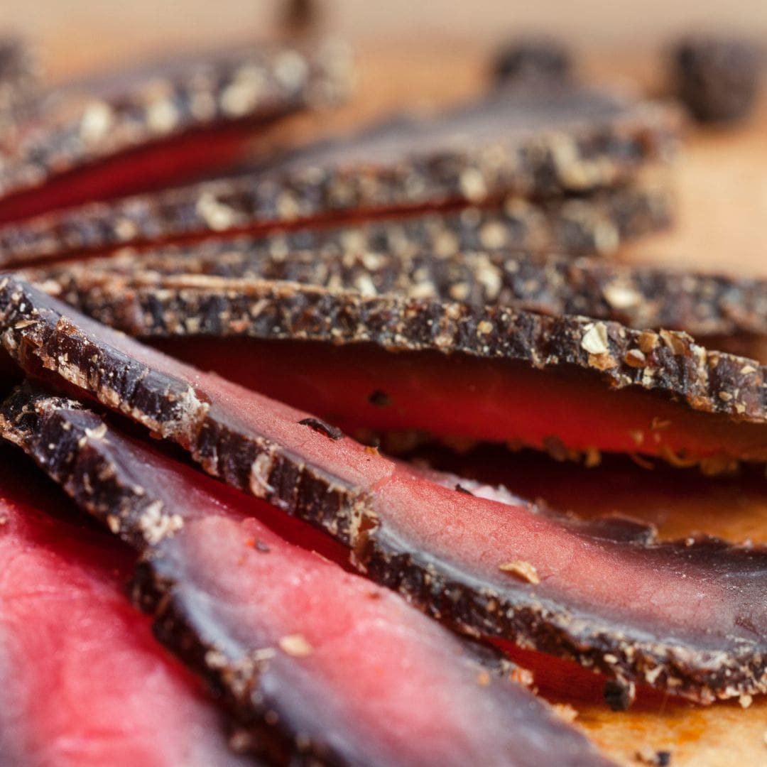 Close-up of sliced biltong meat on a wooden board. Part of Billy Tong's Biltong Snack Packs.