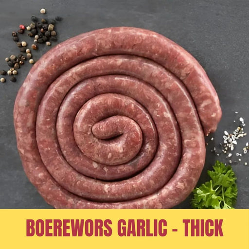 Coiled boerewors garlic thick sausage on a dark surface with spices and herbs.