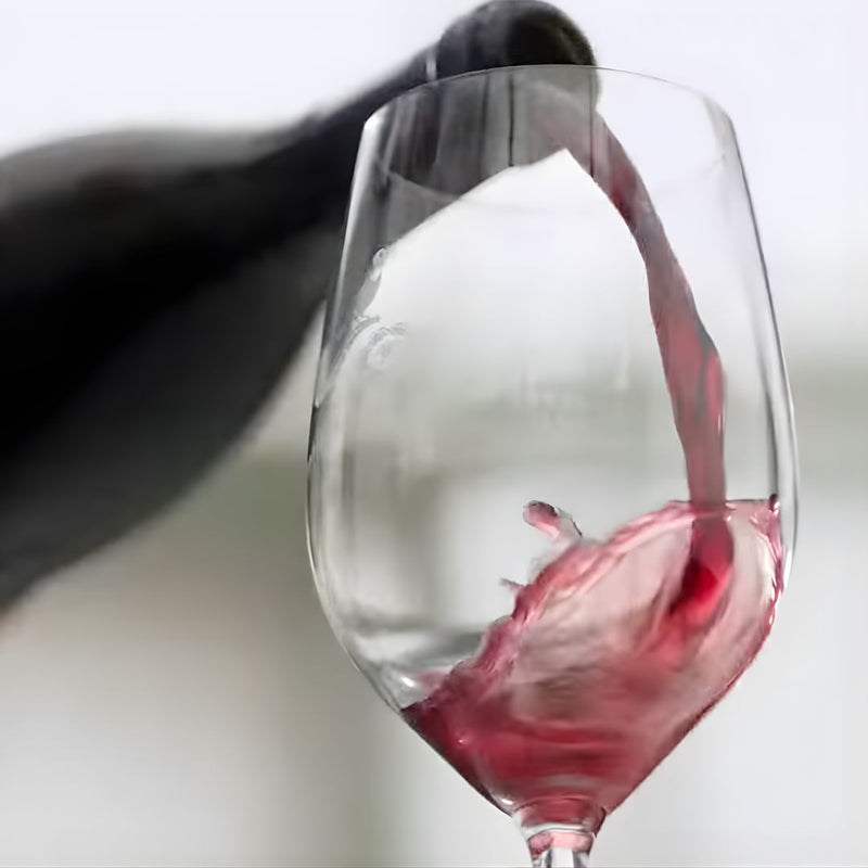 Babylonstoren Shiraz Red wine being poured into a clear glass with a blurred background