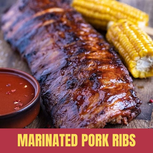 Marinated pork ribs with corn on the cob and a bowl of sauce on a wooden surface.